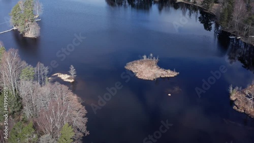 Drone shot orbiting over small island in lake in Sweden during day. Reflections of sky in the lake. photo