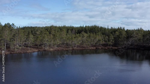 Drone push shot of small Swedish lake revealing vast forests. photo