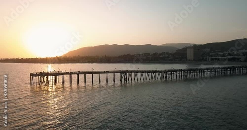 A 4K drone footage of a wooden dock over a calm sea in Ventura, California during sunset photo