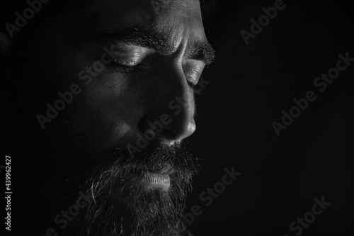 rostro de hombre con sus ojos cerrados en un primer plano y un fondo negro 