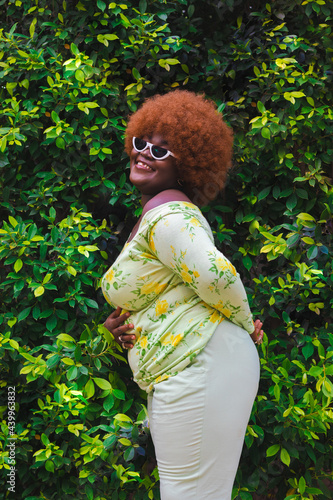 woman posing against a bed of green leaves.