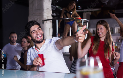 Smiling man and woman on party in the club with cocktails