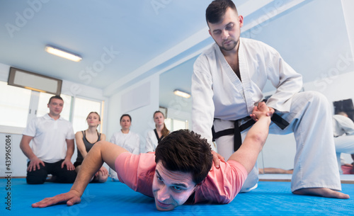 Young spanish man training new taekwondo holds with adults during class.