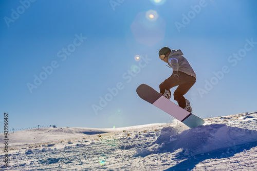 Low-angle shot of an active snowboarder in the Erciyes ski field in Kayseri under a clear blue sky photo
