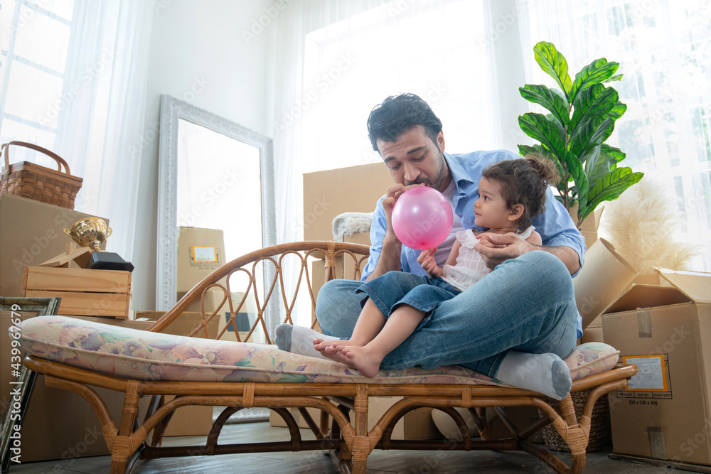 Father and daughter blowing up balloons, having fun together, little girl play balloon with her father in new house at moving day Father and daughter blowing up balloons, having fun together, little girl play balloon with her father in new house at moving day