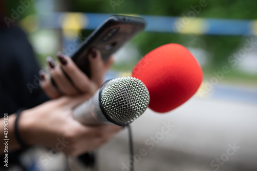 Journalist at news conference, recording notes, holding microphones and smartphone dictaphone