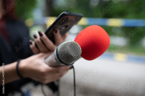 Journalist at news conference, recording notes, holding microphones and smartphone dictaphone © Adam Radosavljevic