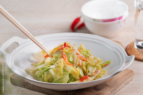 Stir-fried cabbage with sergestid Sakura shrimp in white plate on wooden table background.