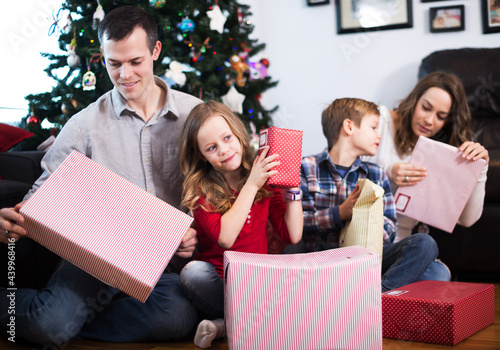Parents with children exchanging gifts during Christmas at home