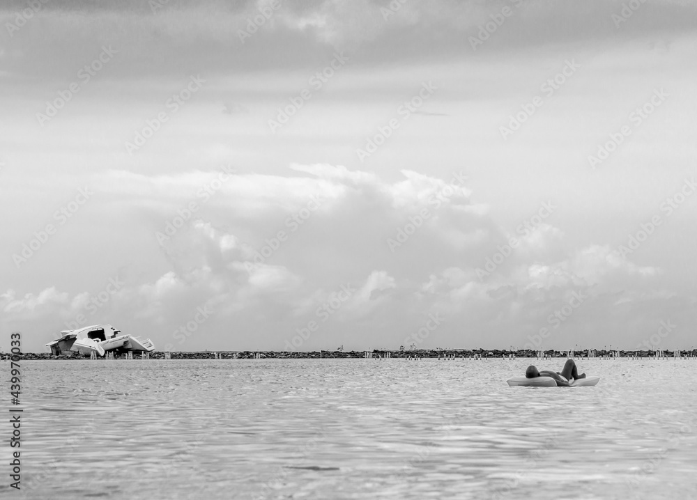 Fototapeta premium Dramatic image of a shipwreck of an abandoned boat off the Caribbean coast with crystal clear water and cloudy skies, in Boca Chica, Dominican Republic.