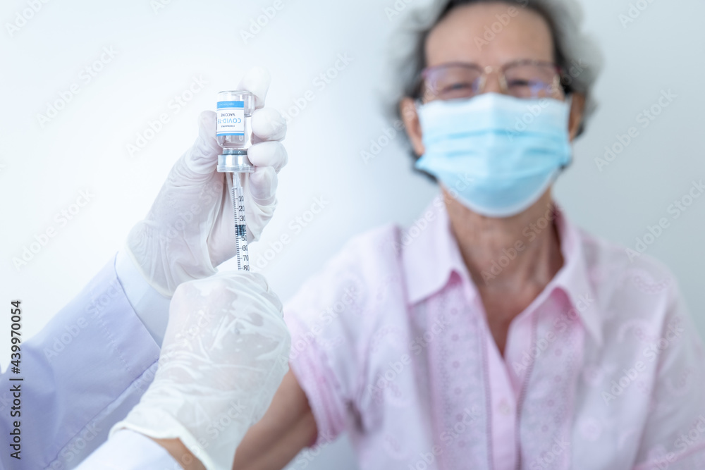 Woman doctor is vaccinating a white-robed Asian woman to protect against the coronavirus or COVID-19 Woman doctor is vaccinating a white-robed Asian woman to protect against the coronavirus or COVID-19