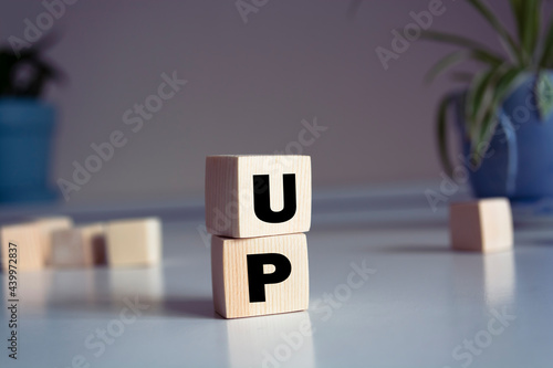 Word UP made from wooden letters on pink background. Concept of growth