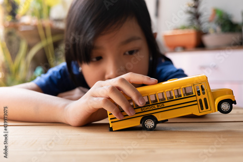 Asian child girls lonely play the yellow toy school bus during their break from school or at home. , Concept Learn at home to stop the transmission of the coronavirus or covid-19