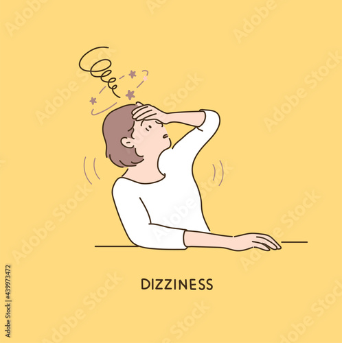 A woman is holding her head in her hands and expressing her dizziness.