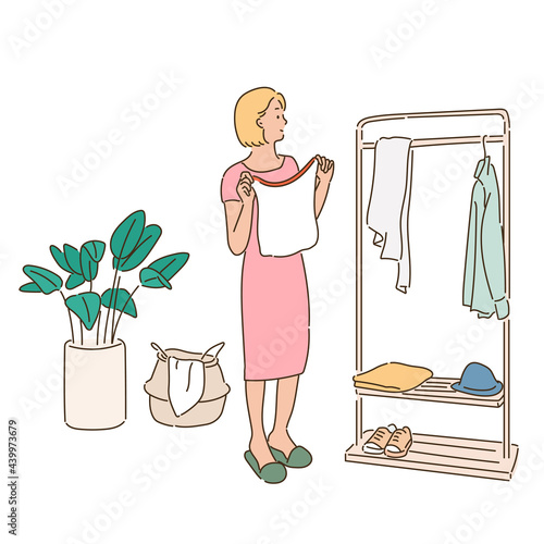 A woman is choosing clothes from hangers in a wardrobe.