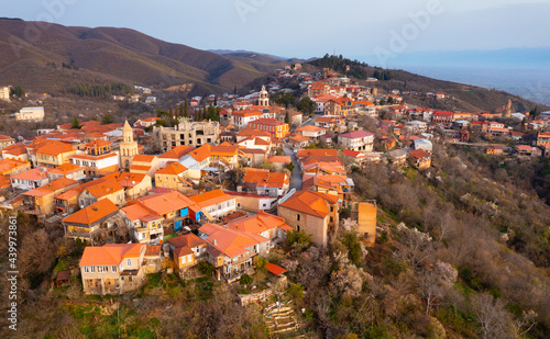 Picturesque aerial view of small Georgian town of Sighnaghi with similar terracotta roofs of houses on steep hill near Gombori Range on spring day, Kakheti, Georgia.. photo
