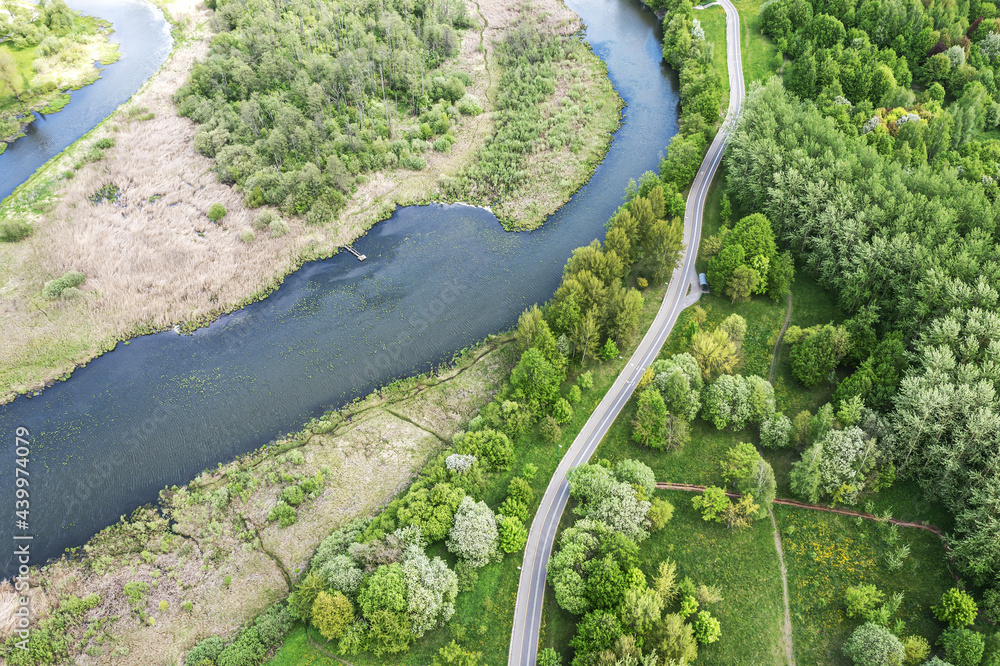 aerial view of bicycle lane with footpath between green trees and river. spring park landscape.