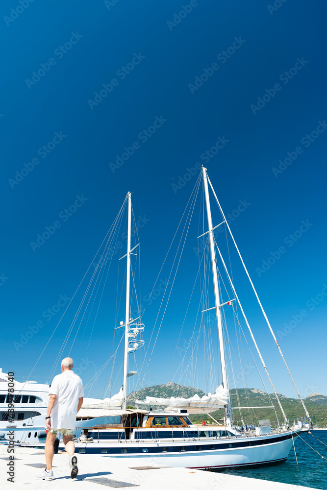 Obraz premium Stunning view of a sailboat moored to a port during a sunny day. Porto Rotondo, Sardinia, Italy.