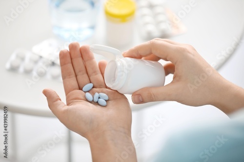 Woman taking pills at home, closeup photo