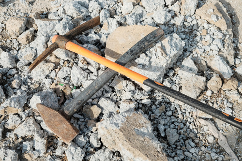 Geological pick with orange handle on the stones next to old hammer