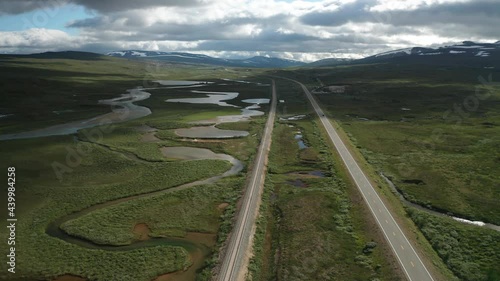 A dynamic flight over a river Luonosjahka, neighboring with an asphalt two-lane automobile road and a railway. Captured in Semska-Stodi natural reservation in the Arctic Circle. photo