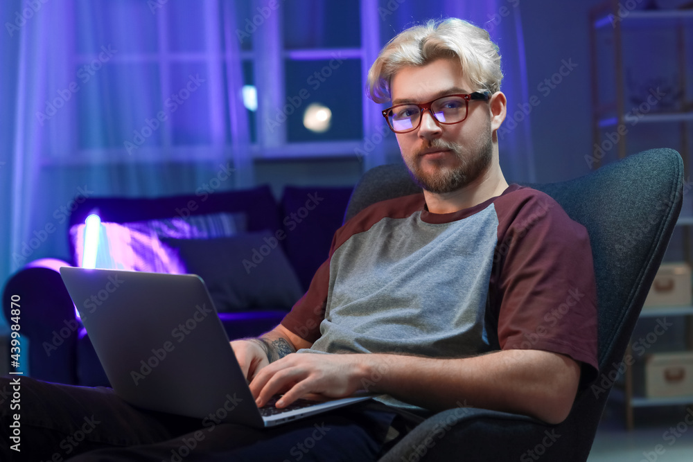 Handsome man using laptop at home late in evening Handsome man using laptop at home late in evening