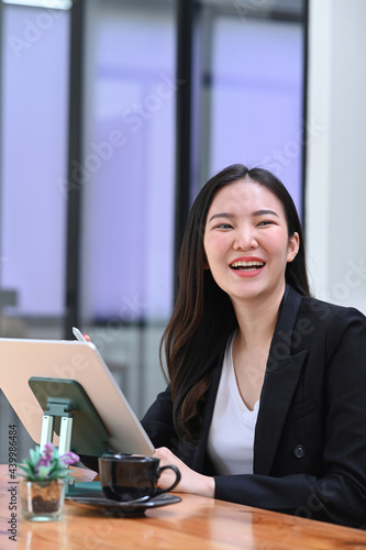 Happy businesswoman sitting at her workplace and smiling to camera.