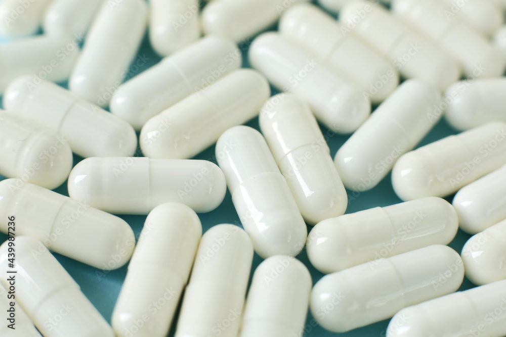 White medical pills isolated on blue background White medical pills isolated on blue background