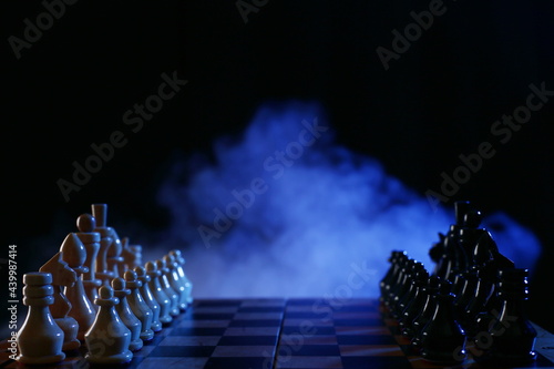 Chess is a board game. Wood chess pieces on a dark background in