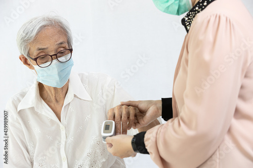 Fotografia Female caregiver with fingertip pulse oximeter,attached on finger of elderly,hea