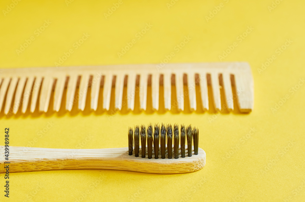 A wooden toothbrush and a wooden comb lie on a yellow background A wooden toothbrush and a wooden comb lie on a yellow background