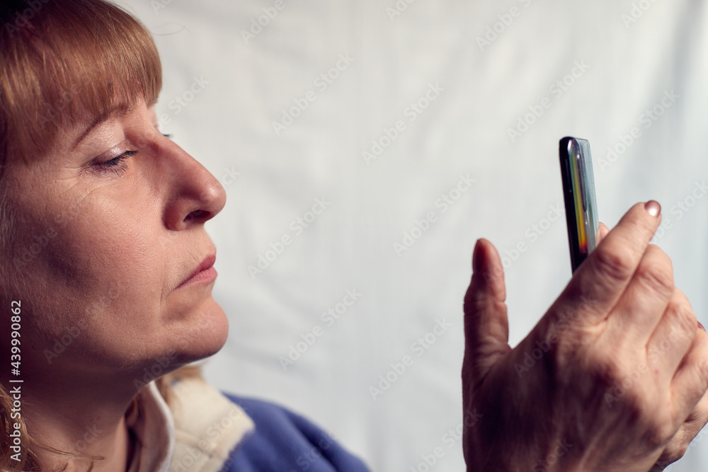 Portrait of a middle-aged woman with cell phone on a white background. Unprofessional female model doing selfie in the room or in the Studio Portrait of a middle-aged woman with cell phone on a white background. Unprofessional female model doing selfie in the room or in the Studio
