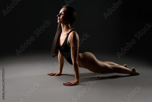 Graceful woman in bodysuit in dark studio