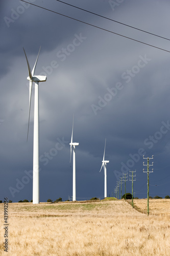 Wind turbines and power lines in paddock with incoming storm photo