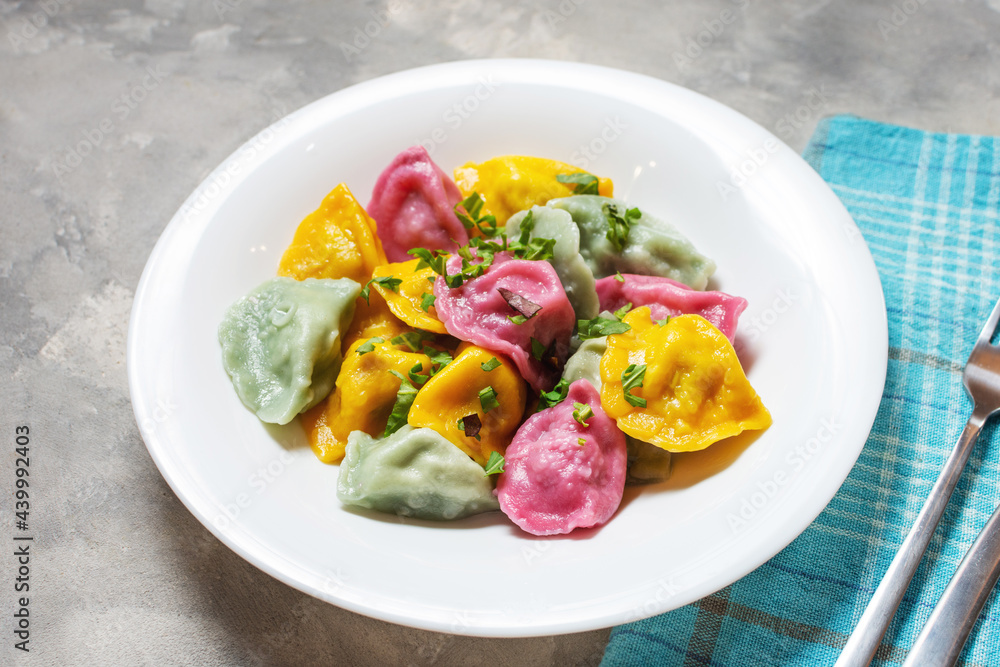 Multi colored dumplings from color dough stuffed with meat on concrete background