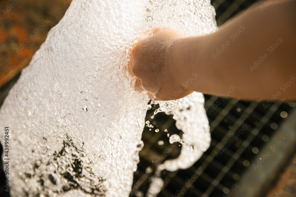 Fountain in the city park.A child's hand touches a stream of water that gushes out from under the grate on the ground. Fountain in the city park.A child's hand touches a stream of water that gushes out from under the grate on the ground.