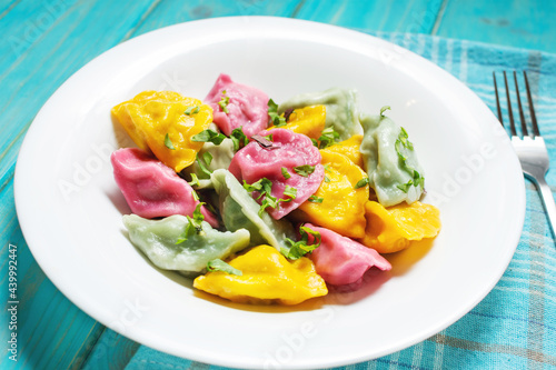 Multi colored dumplings from color dough stuffed with meat on wooden background