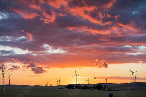 wind turbines in farmland against sunset sky photo