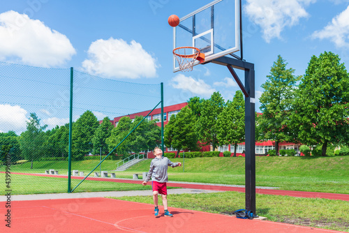 Young boy having fun playing basketball outdoors.nice,cool caucasian alone player playing basketball outdoors.