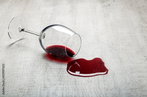 Wooden floor with overturned glass of red wine. Spilled wine on a wooden laminate parquet floor with moisture protection.  photo