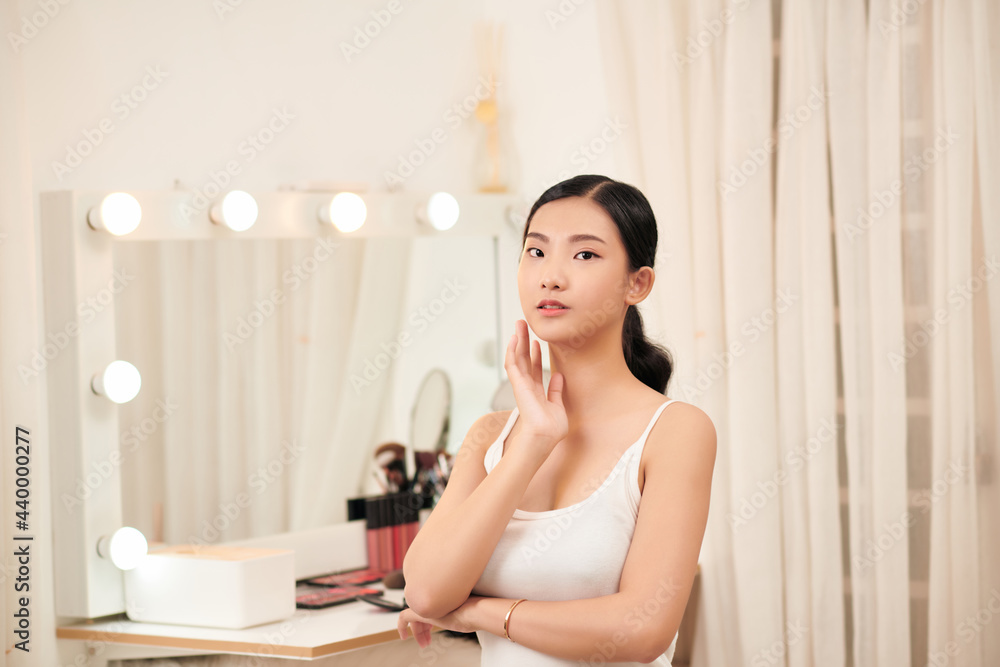Female Skin Care. Young asian woman touching her face and looking to mirror Female Skin Care. Young asian woman touching her face and looking to mirror