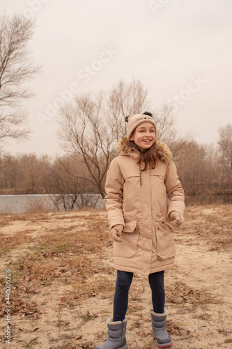 Outdoor portrait of adorable 10- 11 year old girl wearing warm jacket. A schoolgirl in a beige hat.