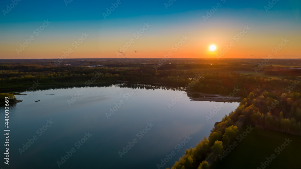 Beautiful aerial view on the forest lake at sunset in Belgium in spring time, shot with a drone. High quality photo
