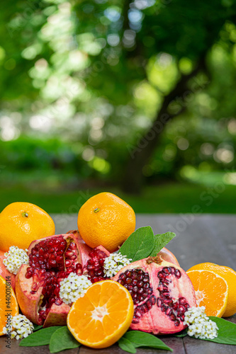 Cut Open Pomegranates and Oranges on a Table Outside with White Flowers