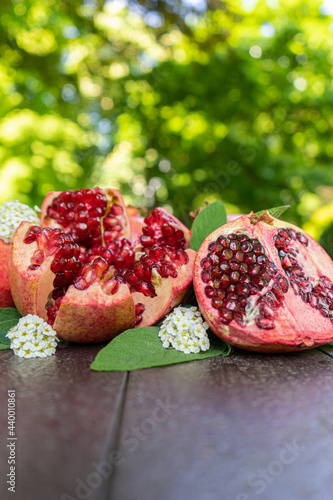 Cut Open Pomegranates on a Wooden Table Outside with White Flowers