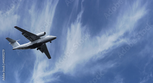The plane took off into the sky. Airplane flight on a background of blue cloudy sky on a clear sunny day.