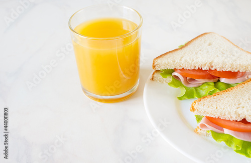 Sandwiches and orange juice on white table. European breakfast