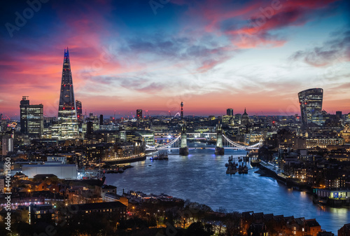 Elevated, panoramic view to the lit skyline of London, United Kingdom, just after sunset with Tower Bridge and modern office buildings along the Thames river © moofushi