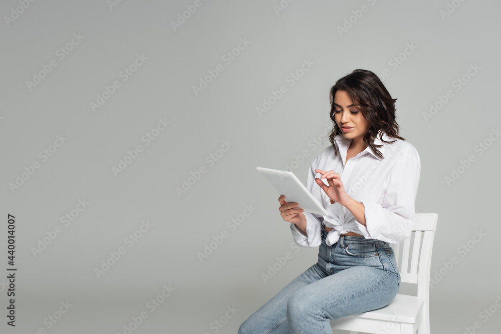Pretty woman using digital tablet isolated on grey Pretty woman using digital tablet isolated on grey
