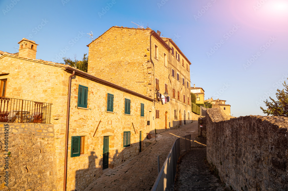 Volterra, Tuscany, Italy. August 2020. The walls of the historic village. The warm light of the late afternoon enhances the massive stone wall, at its foot the perimeter path. Tuscan landscape.